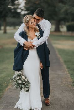 a bride and groom embracing each other on a path