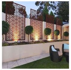 an outdoor seating area is lit up at night with lights shining on the walls and trees