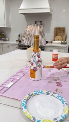 a woman is sitting at the kitchen table with her plate and wine bottle on it