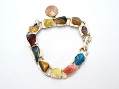 Multi Color Jewelry - This is a gold tone link bracelet with nugget gems of turquoise, amethyst, jasper, agate, tiger's eye, rhodocrosite and more. It has a round red enamel New Mexico charm that measures .5" in diameter, bracelet is 7" long and .38" wide. Multicolor Metal Bracelets With Stones, Multicolor Costume Jewelry Bracelets With Jewels, Multicolor Jewel Costume Jewelry Bracelets, Adjustable Multicolor Gemstone Bracelets, Adjustable Multicolor Bracelets With Gemstone Accents, Vintage Multicolor Stone Bracelets, Bohemian Multicolor Gemstone Bracelets, Adjustable Costume Jewelry Bracelets With Stones, Multicolor Jewelry