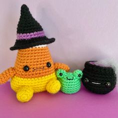 two small crocheted toys sitting next to each other on a purple surface with a white wall in the background