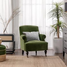 a green chair sitting in front of a window next to a potted plant