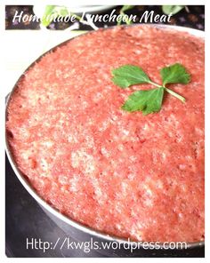 a pan filled with meat covered in sauce and garnished with a green leaf