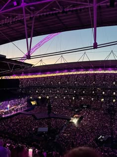 an arena full of people at a concert with purple lighting on the ceiling and in the stands