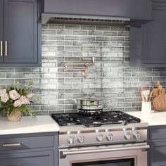 a stove top oven sitting inside of a kitchen next to gray cabinets and counter tops