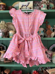 Sweet well constructed vintage romper. Smaller scale plaid with pink background with blue, yellow and white accents. Ruffles galore. Loose fitting short with button closure in the style of a diaper with an apron tie skirt. Open back with tie at the neck. Needs a little repair along the neck line. Good vintage condition with small stain noted in the crotch area. Tag removed, maker and size unknown.  Measures 12 inches across the top and waist,  arm opening 6 inches measured flat.  The rest is free flowing. Retro Pink Jumpsuits And Rompers For Summer, Pink Retro Jumpsuits And Rompers For Spring, Retro Pink Summer Jumpsuits And Rompers, Pink Retro Summer Jumpsuits And Rompers, Plaid Romper, Vintage Romper, Cary Nc, Tie Skirt, Free Flowing