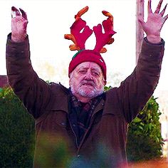 an older man wearing a red hat and holding his hands up in the air