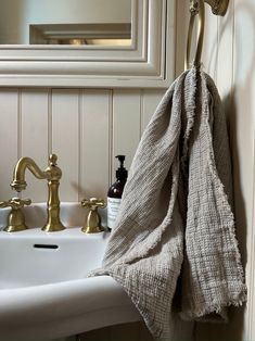 a towel hanging on the side of a bathroom sink next to a faucet