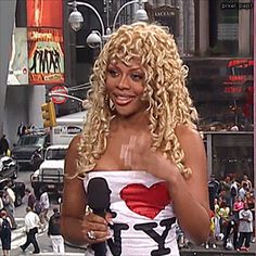 a woman with blonde hair is holding a microphone and wearing a dress that says i love ny