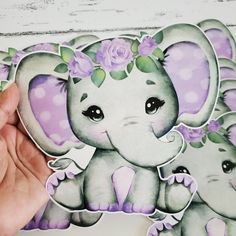 a hand holding up a sticker with an elephant and baby elephant on it's back