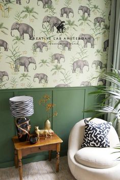 an elephant wallpaper in a living room next to a chair and table with a lamp on it