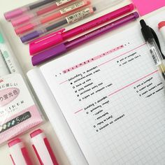 some pens and markers are on top of a notepad with other writing materials around it