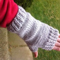 a woman's hand wearing a knitted arm warmer on top of a sidewalk