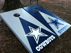 two blue and white cornhole boards with the word cowboys written on them in front of a tree