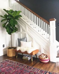 a living room with a rug, chair and plant next to the stair banister