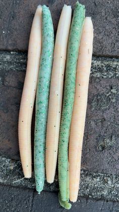 three pieces of green and white food sitting on top of a brick floor next to each other