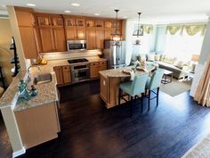 a large open concept kitchen and living room with hardwood flooring, stainless steel appliances