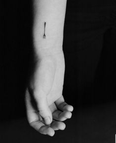 a black and white photo of a person's hand with a small tattoo on it