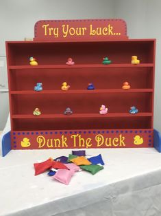 there is a red book shelf with toys on it and the words, try your luck dunk the duck