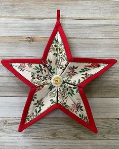 a red and white star shaped ornament hanging on a wooden wall