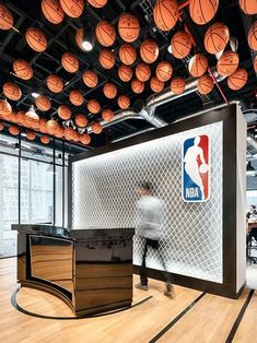 a man is walking in front of basketballs hanging from the ceiling and on the wall