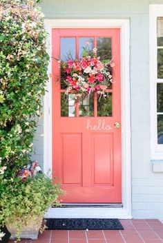 a bright pink door with the word hello written on it and flowers in front of it