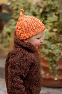 a small child wearing a brown jacket and orange hat