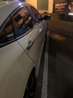 a white car parked in front of a building on the side of a street at night