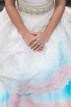 a woman in a wedding dress holding her hands on her chest and wearing a blue ring