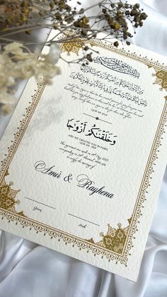 an ornate wedding card with gold trimmings and white paper on a satin background