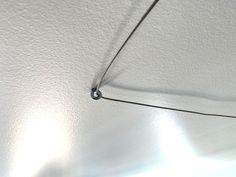 a close up of a string attached to a ceiling with light shining on the wall behind it