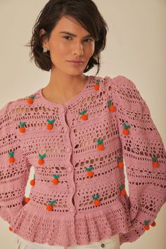 a woman wearing a pink crocheted sweater with oranges on it