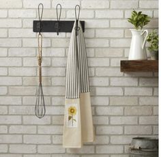 two kitchen towels hanging on a brick wall next to a rack with utensils