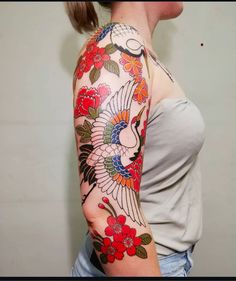 a woman with a tattoo on her arm is looking at the camera and has red flowers in it