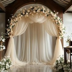 a wedding arch decorated with white flowers and greenery