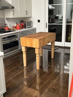 a wooden table sitting in the middle of a kitchen next to a stove top oven