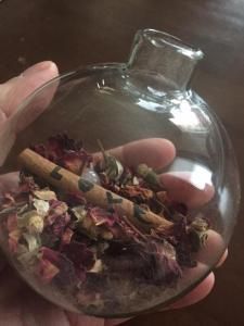 a person holding a glass bowl filled with different types of herbs and spices in it