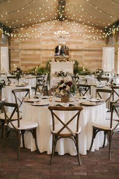 the tables are set up with white linens and wooden chairs for an elegant reception