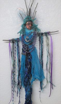 a sculpture made out of yarn and beads is hanging on the wall with chains attached to it