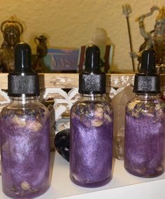 three bottles filled with purple liquid sitting on top of a counter