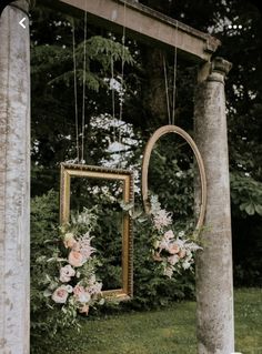 an old photo frame with flowers hanging from it's sides in front of a tree