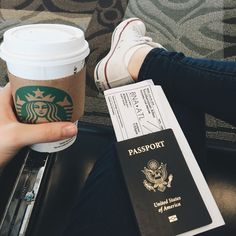 a person holding a passport and a cup of coffee