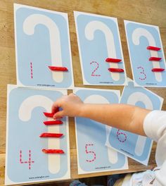 a child's hand is touching the numbers on paper