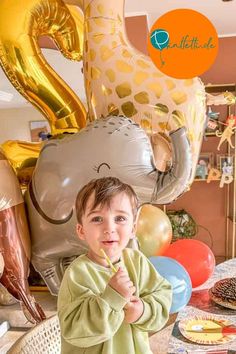 a little boy that is standing in front of some balloons