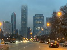 cars are driving down the street in front of tall buildings at night with lights on