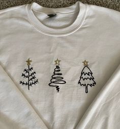 three embroidered christmas trees on a white shirt