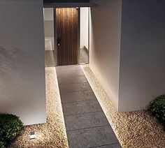 an entrance to a house with lights on the walkway and grass in front of it