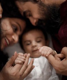 a man and woman holding a baby in their arms