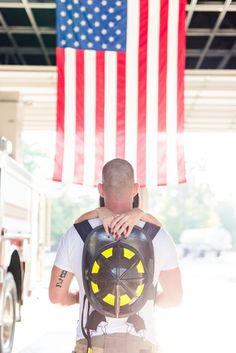 a fireman hugging his friend in front of an american flag