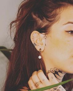 a woman with tattoos and piercings on her ear